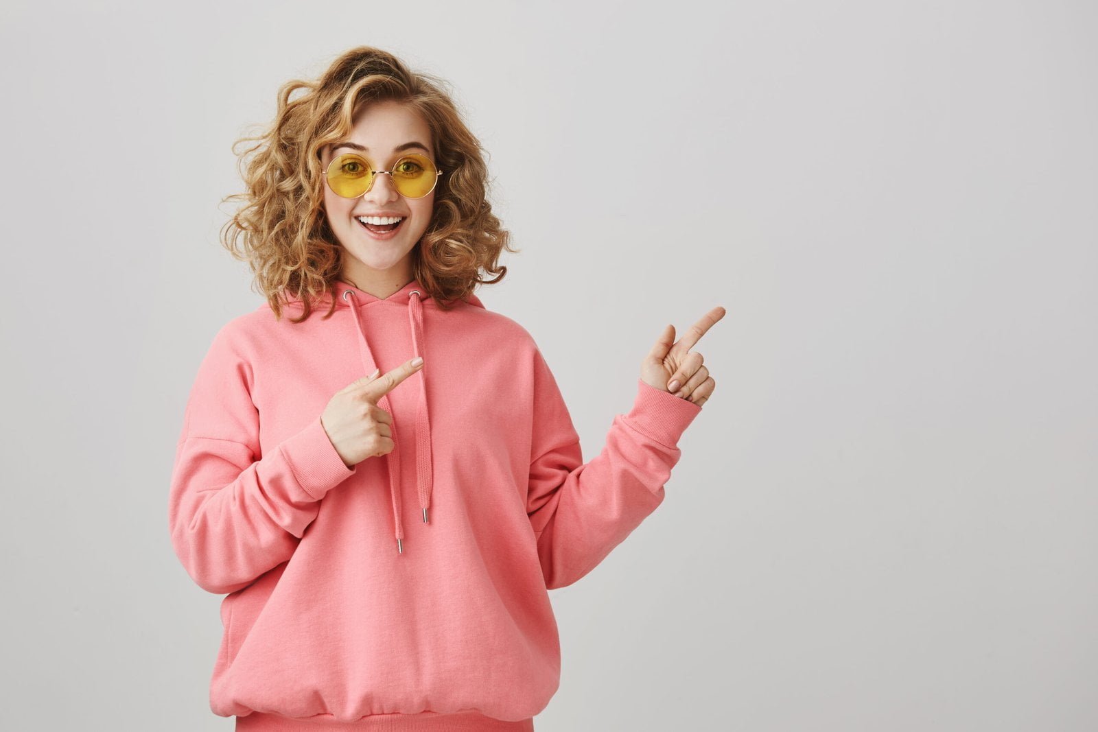 excited-stylish-curly-haired-girl-sunglasses-pointing-right-showing-way-scaled.jpg